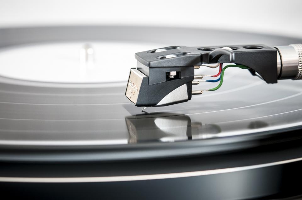 A cartridge and stylus resting on a spinning record